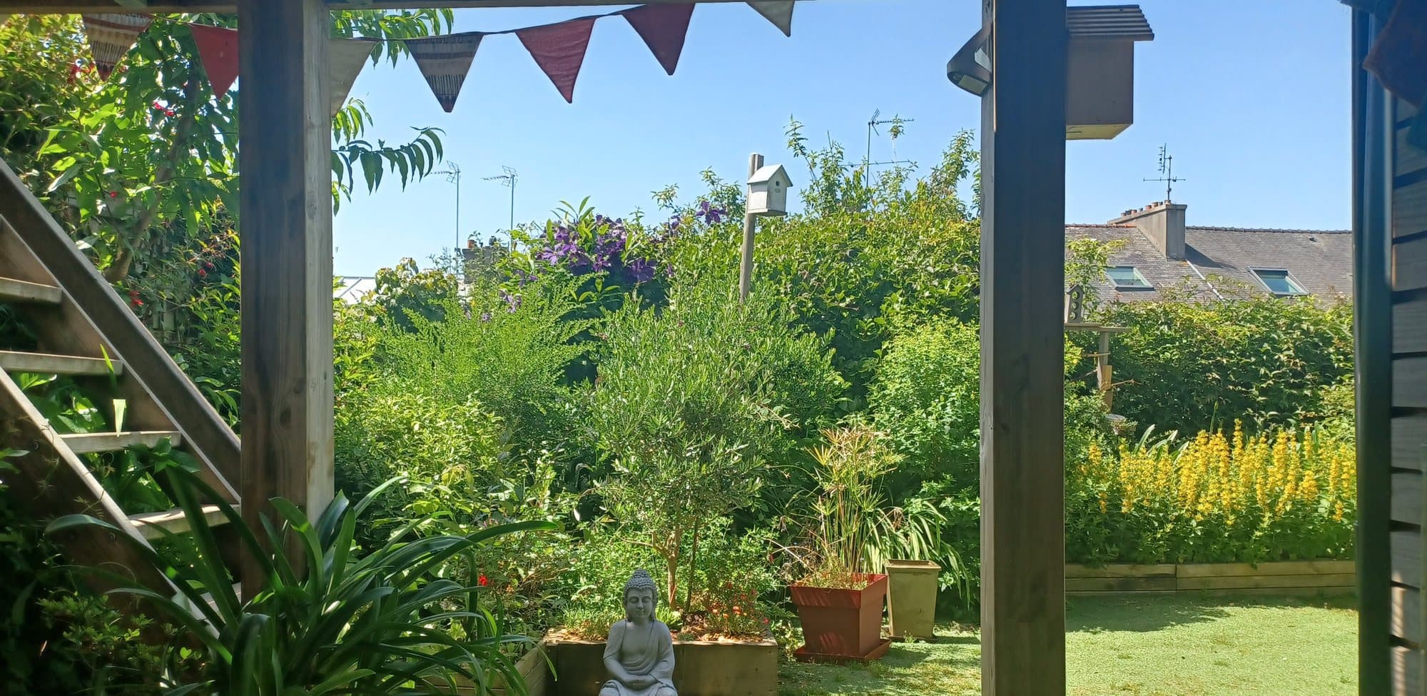 Jardin de Quiétude à Brest, statue de Bouddha, fanions et verdure.