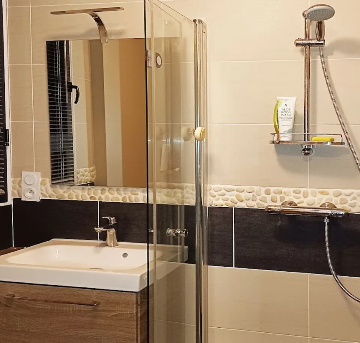 Salle d'eau de Quiétude à Brest, douche, vasque et frise en galets pour se rafraîchir avant ou après le soin.