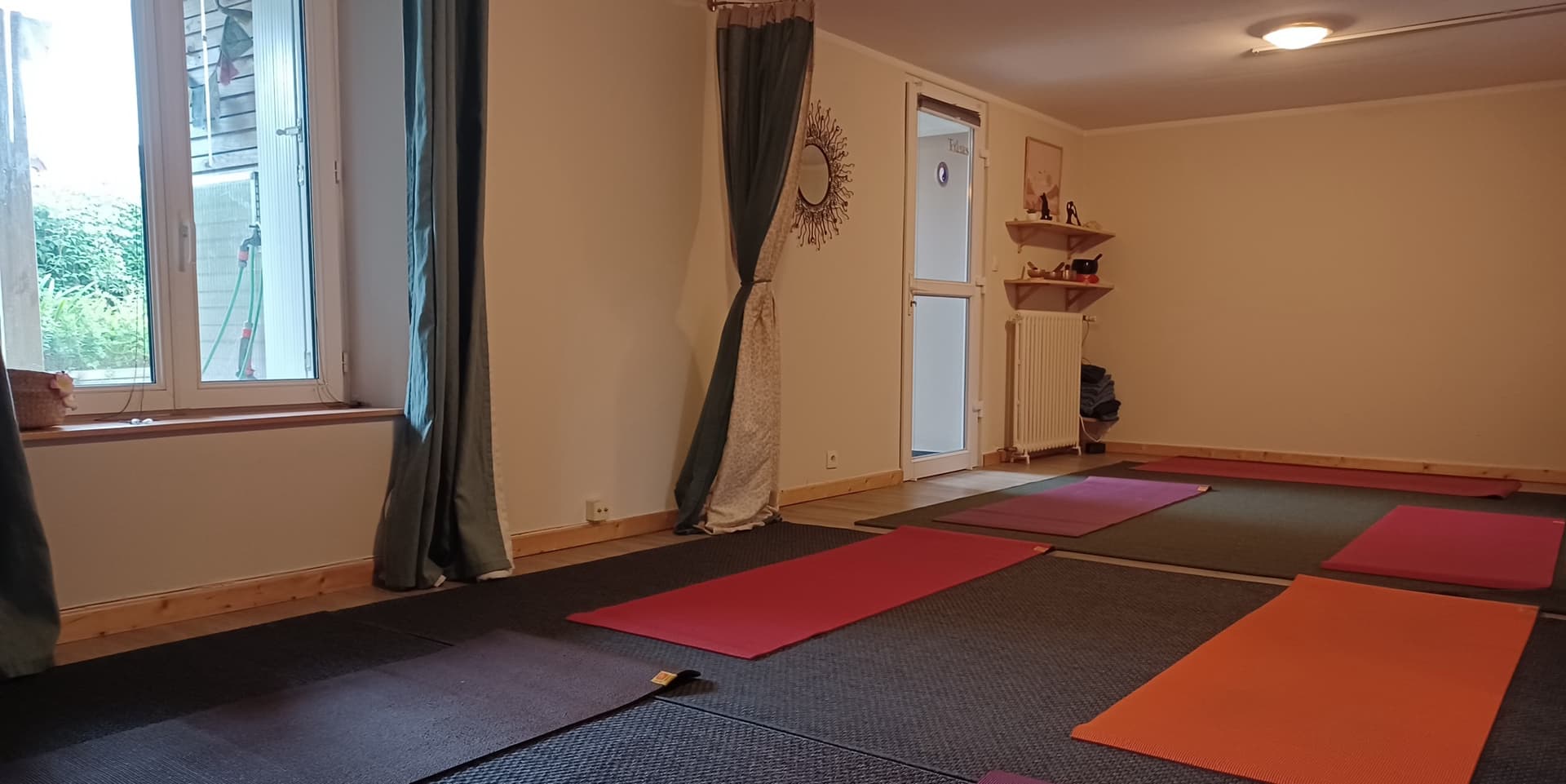 La salle de yoga de Quiétude à Brest, tapis colorés sur le parquet, rideaux et vue sur le jardin, rue Jules Favre.